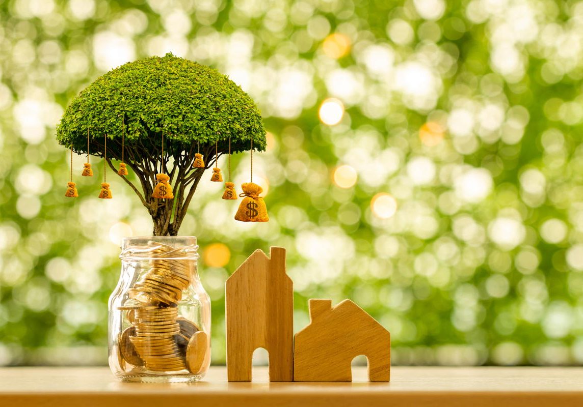 Home model and bottle bank and coin with growing value and money bag of tree as destinations put on the table in the public park, Business investment and loan for real estate or buy house concept.